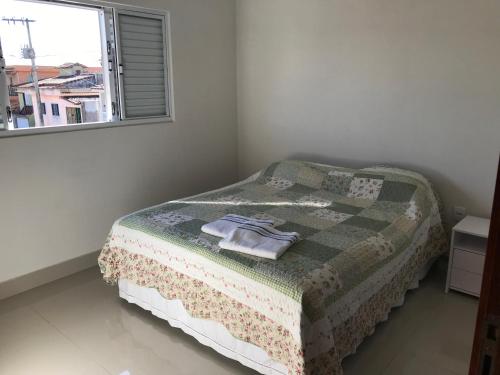 een slaapkamer met een bed met een deken en een raam bij Pousada da Tia Cida in Capitólio