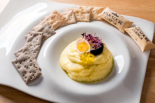 a plate of food with an egg and crackers at Parador de Cuenca in Cuenca