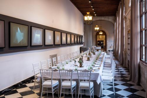 a long table with white tables and chairs in a room at Parador de Cuenca in Cuenca