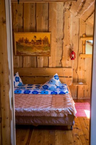 a bedroom with a bed in a wooden cabin at Adeles sodyba in Sturmai