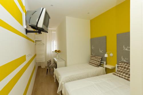 a room with two beds and a tv on a wall at Turismo do Seculo in Estoril
