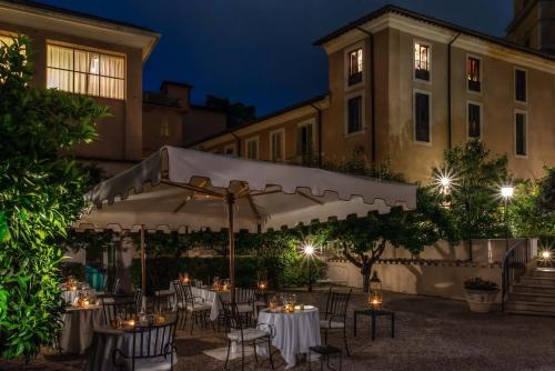 a group of tables and chairs under a white umbrella at Donna Camilla Savelli - VRetreats in Rome