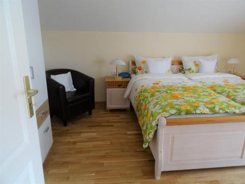 a bedroom with a bed and a black chair at Gästehaus Casa Cristina in Bad Krozingen