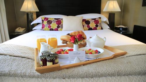 a tray with food and drinks on a bed at The Beaufort in London