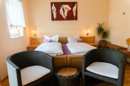 two beds in a room with wicker chairs at Pension Haas-Hotel am Turm in Rottweil