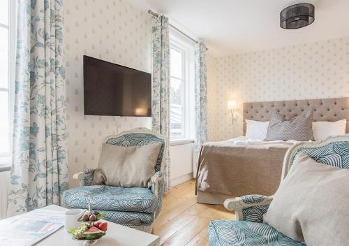 a bedroom with a bed and a chair and a tv at Stufvenäs Gästgifveri in Söderåkra