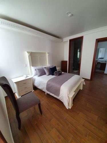 a bedroom with a large bed and a chair at Hotel Estancia Real in Tepatitlán de Morelos