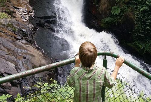 a woman looking over a fence at a waterfall at Camping du Lac in Marcillac-la-Croisille