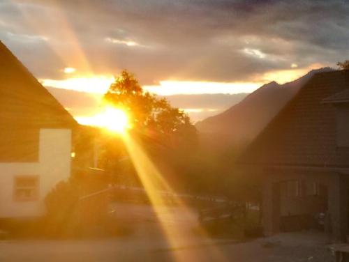 a sunset with the sun setting behind some houses at Apartment Vorderstoder in Rossleithen