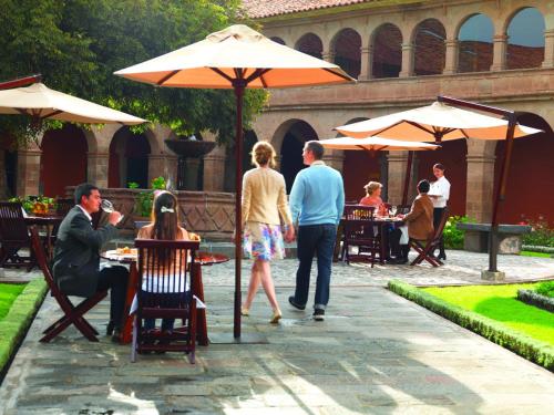 a group of people sitting at tables under an umbrella at Monasterio, A Belmond Hotel, Cusco in Cusco