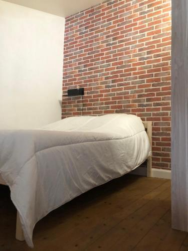 un lit dans une chambre avec un mur de briques dans l'établissement Villa Royale - T1 bis de 31m2 - proche centre ville, à La Rochelle