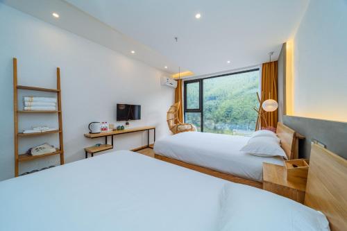 two beds in a room with a window at Moganshan Pinhouwu Hotel in Deqing