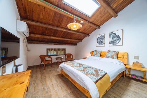 a bedroom with a large bed and a table at Moganshan Pinhouwu Hotel in Deqing