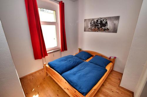 ein Schlafzimmer mit einem Bett mit blauen Kissen und einem Fenster in der Unterkunft Kunterbunt in Naumburg