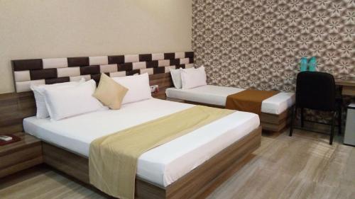 NavsāriにあるHotel Shahi Darbarのホテルルーム ベッド2台&椅子付