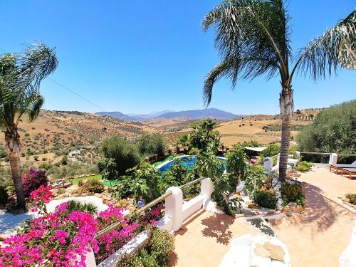 a resort with a pool and palm trees and flowers at Finca Gran Cerros in Alora