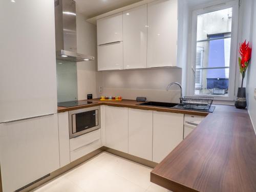 une cuisine avec des armoires blanches et un comptoir en bois dans l'établissement Appartement centre de Cannes, à Cannes