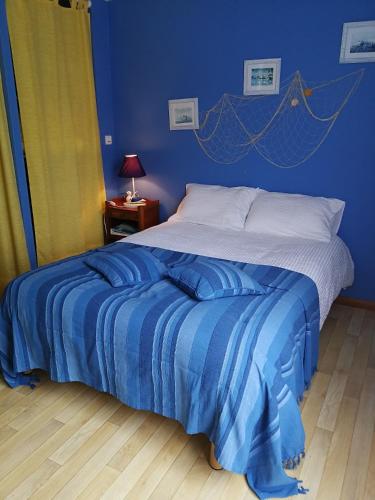 une chambre avec un lit avec un mur bleu dans l'établissement Auberge du Vieux Tour, à Canapville