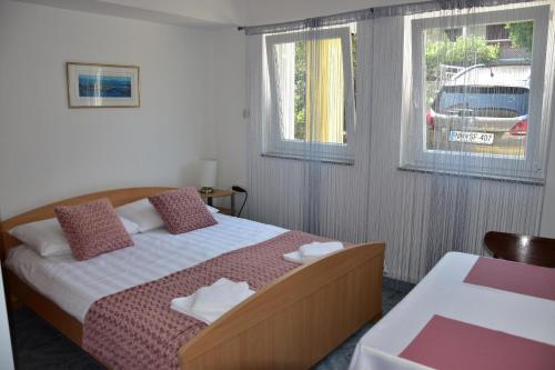 sypialnia z łóżkiem i 2 oknami w obiekcie Apartmani Novosel w mieście Šilo