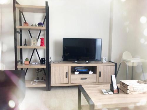 a television on a wooden entertainment center in a living room at By The Sea BeachFront Penang in Batu Ferringhi