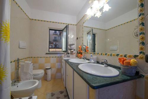 a bathroom with two sinks and a toilet and a mirror at Mansarda Ciaciano in Bomerano