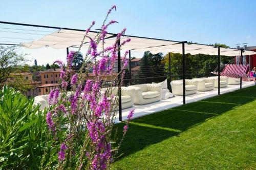 a row of white couches on a rooftop with purple flowers at Albergo Ristorante Madonnina in Cantello