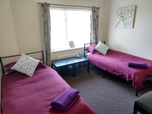 two beds in a room with a window at Rowe Gardens - Self Catering - Guesthouse Style - Comfortable Twin or Double Rooms - Quiet Residential Area in Workington