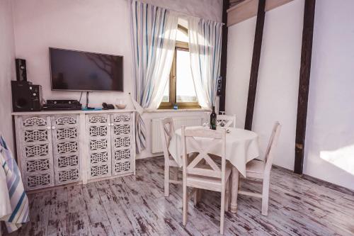 a white dining room with a table and a television at Pensjonat Kolory Świata in Solec-Zdrój