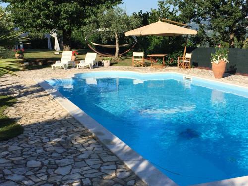 a blue swimming pool with chairs and an umbrella at VILLA "Casa al Chiazzullo" in Mirabella Eclano