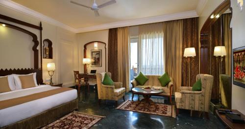 Habitación de hotel con cama, mesa y sillas en Indana Palace, Jodhpur en Jodhpur