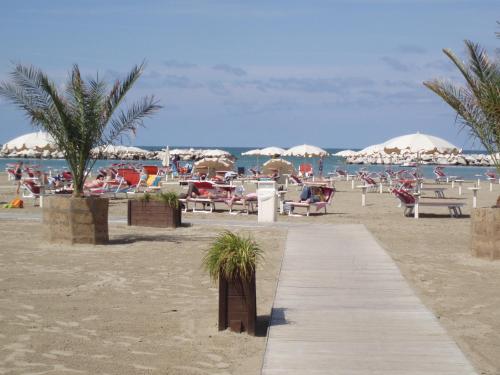 un sentiero sulla spiaggia con sedie e ombrelloni di Hotel Del Vecchio a Rimini