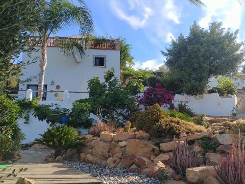 a garden with a white house and trees and rocks at Finca Gran Cerros in Alora