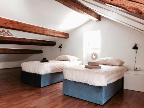 2 bedden in een kamer met witte muren en houten plafonds bij Casa Bibiana in Koper