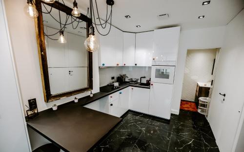 - une cuisine avec des placards blancs et un miroir dans l'établissement Studio les Parmentiers, à Metz