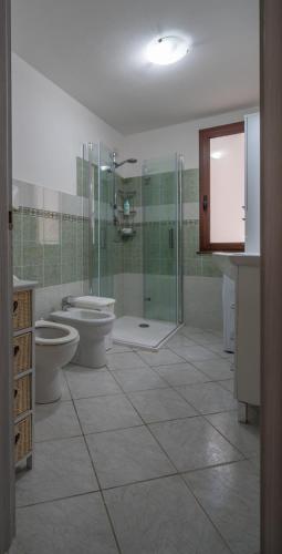 a bathroom with two toilets and a glass shower at Appartamento Belvedere Sassos in Tresnuraghes