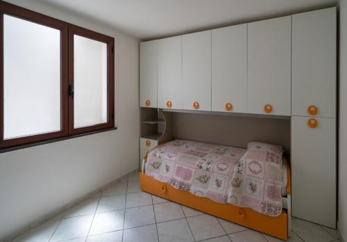 a small bedroom with a bed and two windows at Appartamento Belvedere Sassos in Tresnuraghes