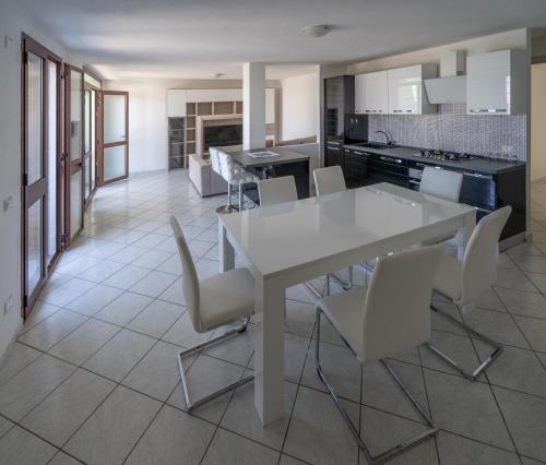 cocina y comedor con mesa blanca y sillas en Appartamento Belvedere Sassos, en Tresnuraghes