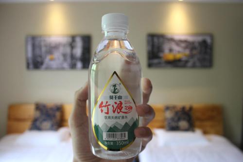 a person holding a bottle with a sign on it at Moganshan Pinhouwu Hotel in Deqing