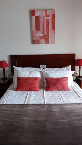a large bed with two red pillows on it at Country House Alfarim in Alfarim