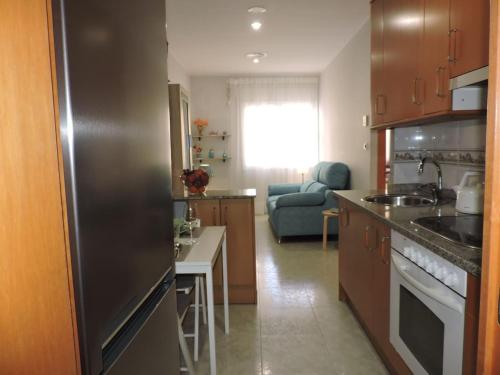 a kitchen with a stainless steel refrigerator and a living room at Carrer Sant Pere Pescador 20 in Blanes