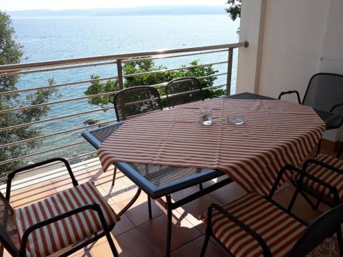 a table and chairs on a balcony with the ocean at App LOLLY in Selce