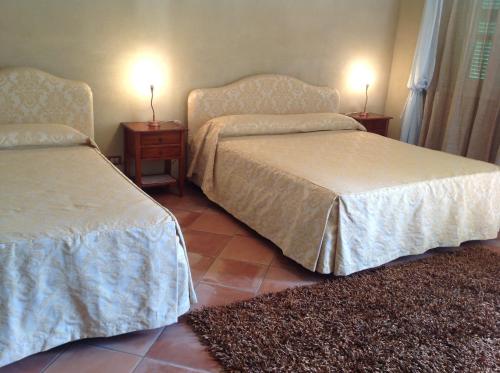 two beds in a room with two tables and two lamps at Locanda San Lorenzo in Roddino