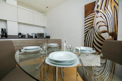 a dining room with a glass table with plates on it at Orion Marina Sea View - Parking - by Brighton Holiday Lets in Brighton & Hove