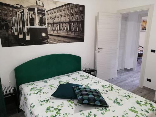 a bed with a green headboard and a picture of a tram at Casa Bumbunin, vicino al centro e al Politecnico in Turin