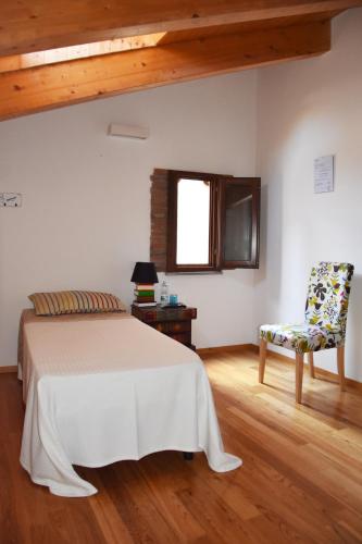 a bedroom with a bed and a chair and a window at Al Libro Letto in Viterbo