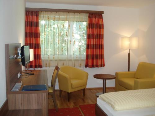 ein Hotelzimmer mit einem Schreibtisch, einem Bett und einem Fenster in der Unterkunft Hotel Almtalerhof in Linz