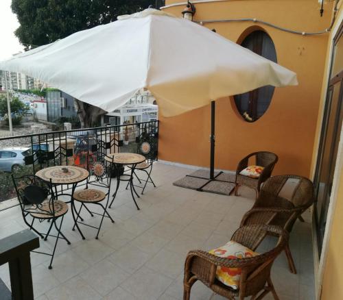 a patio with tables and chairs and an umbrella at Casa Vacanze LIBERTY in Licata