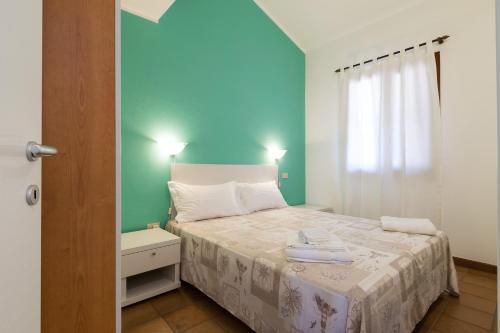 a small bedroom with a bed and a blue wall at Residenza Solemar in Bosa Marina