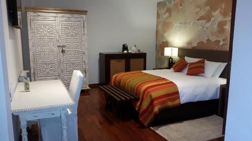 a bedroom with a bed and a table and a desk at Tocuyeros Boutique Hotel in Cusco