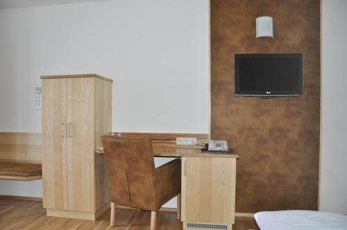 a desk with a chair and a television on a wall at Hotel Almtalerhof in Linz